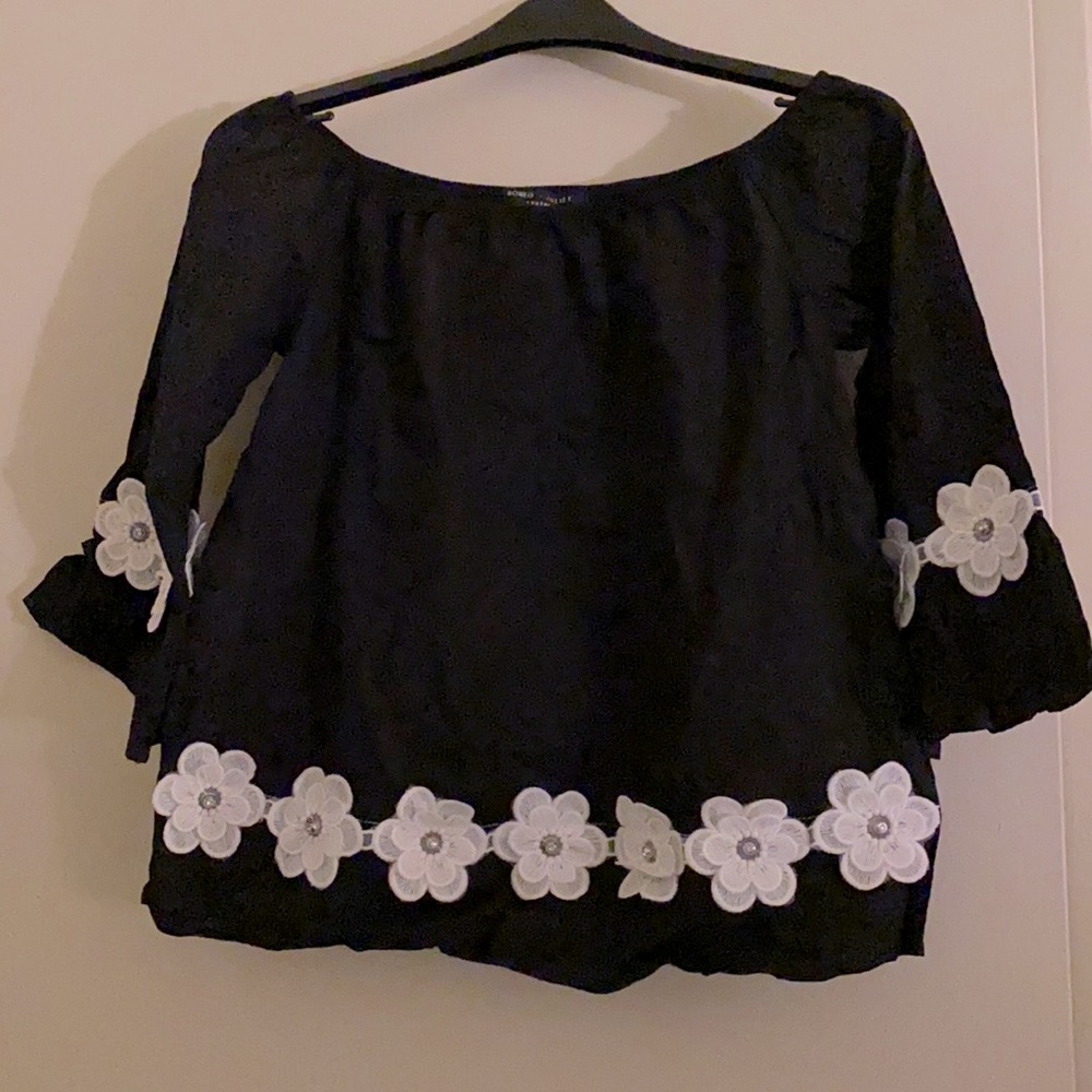 Black top with white flower appliqué trim on sleeves and front.